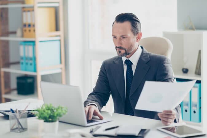 Man analyzing papers and screen